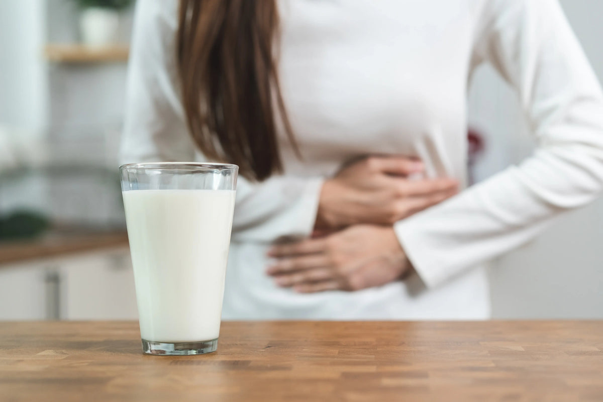 Frau mit Bauchschmerzen mit einem Glas Milch, Laktoseintoranz